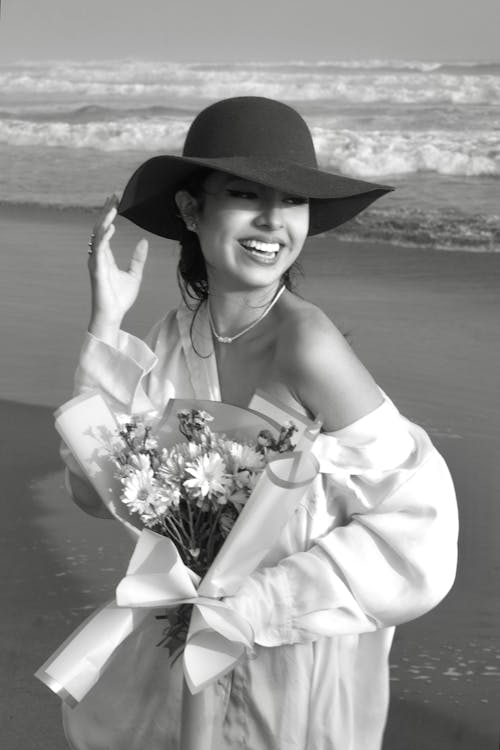 Smiling Woman Standing with Bouquet on Beach