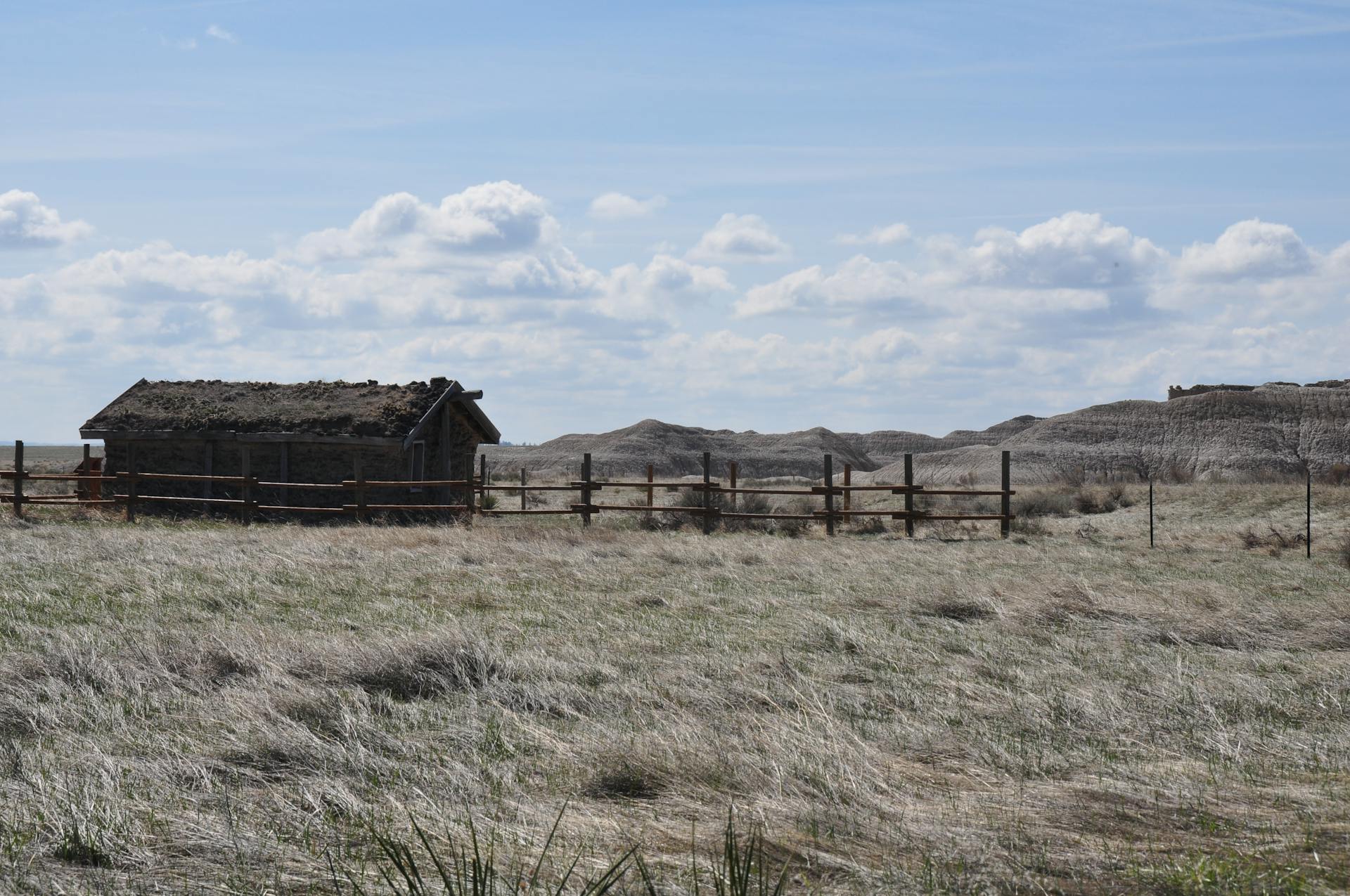 A lonely rustic cabin in the vast fields of Crawford, Colorado, under a bright sky.