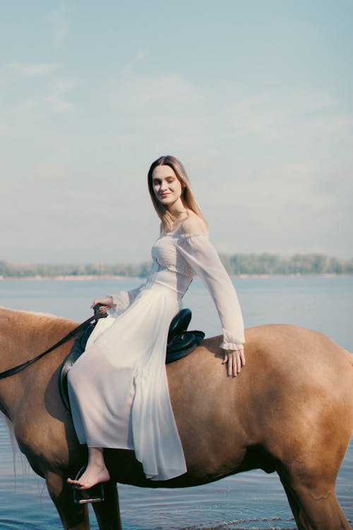 Model Woman in Long Sleeved Dress Riding on Horse