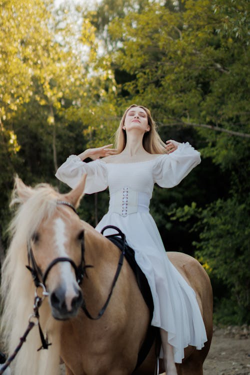 Woman in Long Sleeved Dress Riding on Horse