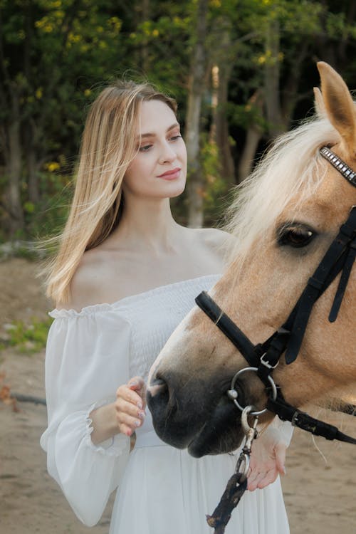 Woman in Long Sleeved Dress Touching Horse