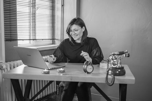 A young woman working on her laptop in a vintage-style office setting.
