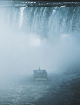 A tourist boat approaches the misty base of the breathtaking Niagara Falls.