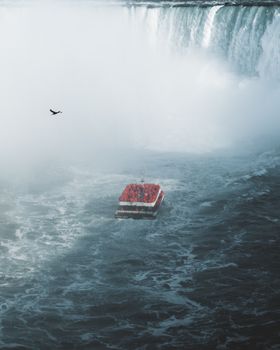 A tourist boat braves the misty waters near the majestic Niagara Falls, showcasing adventure and natural beauty.
