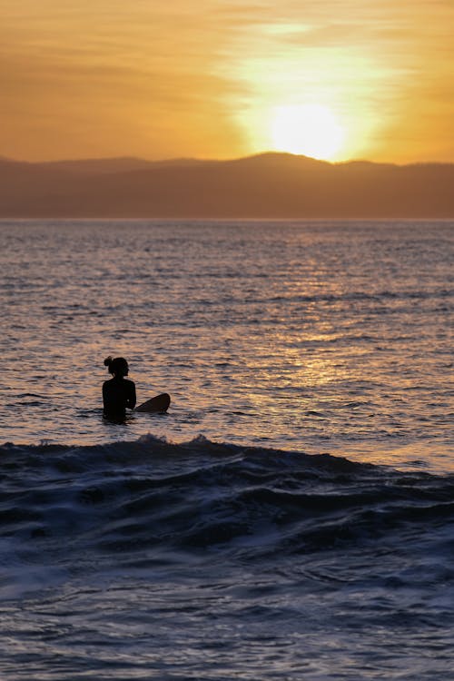 Silhouette of a Woman in the Sea at Sunset 