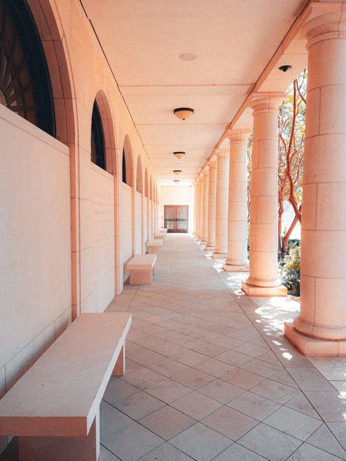 Free A serene colonnade with benches and classic stone columns. Soft lighting creates an elegant perspective. Stock Photo
