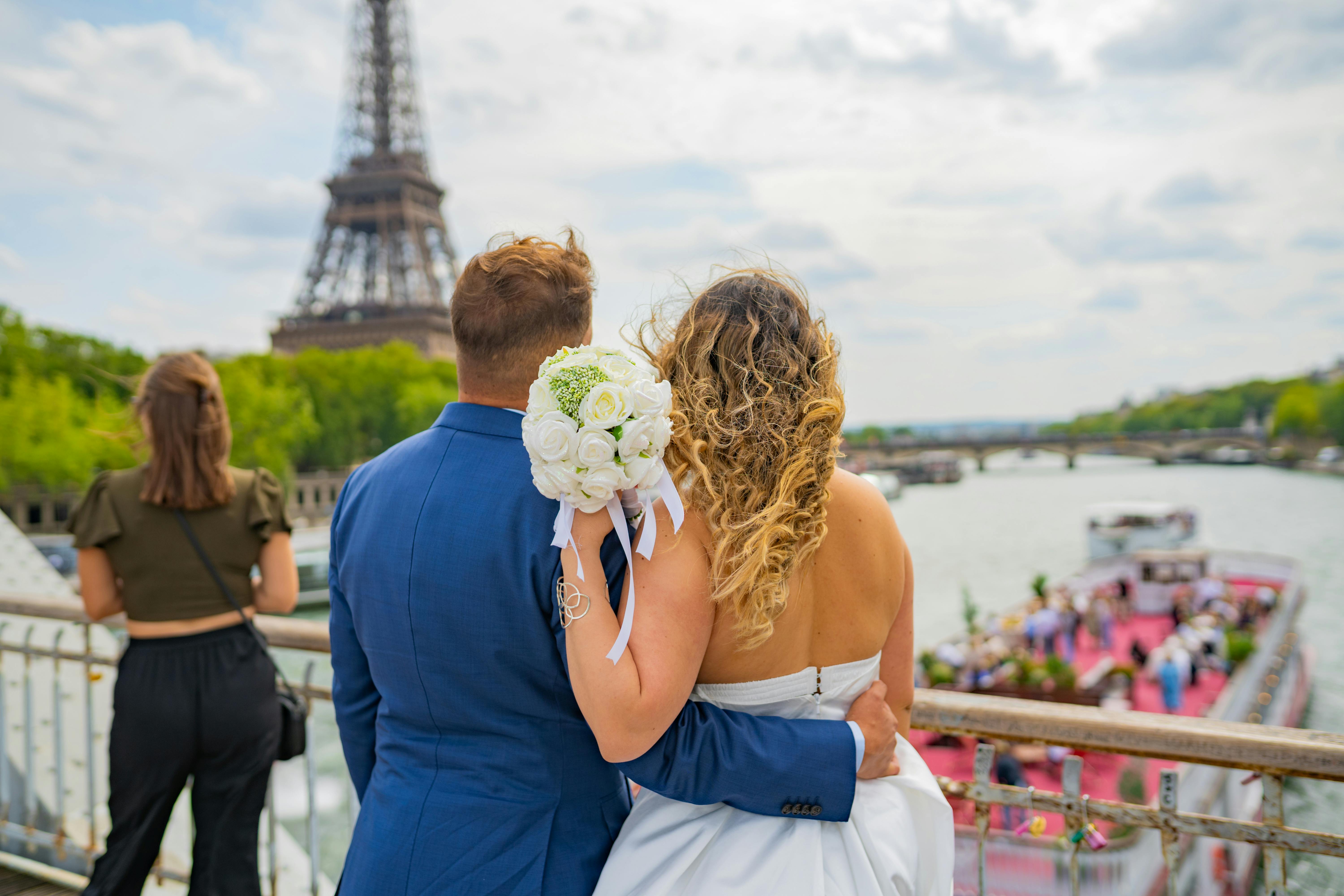 Newlyweds embracing by the Seine River with the Eiffel Tower in the backdrop, Paris.