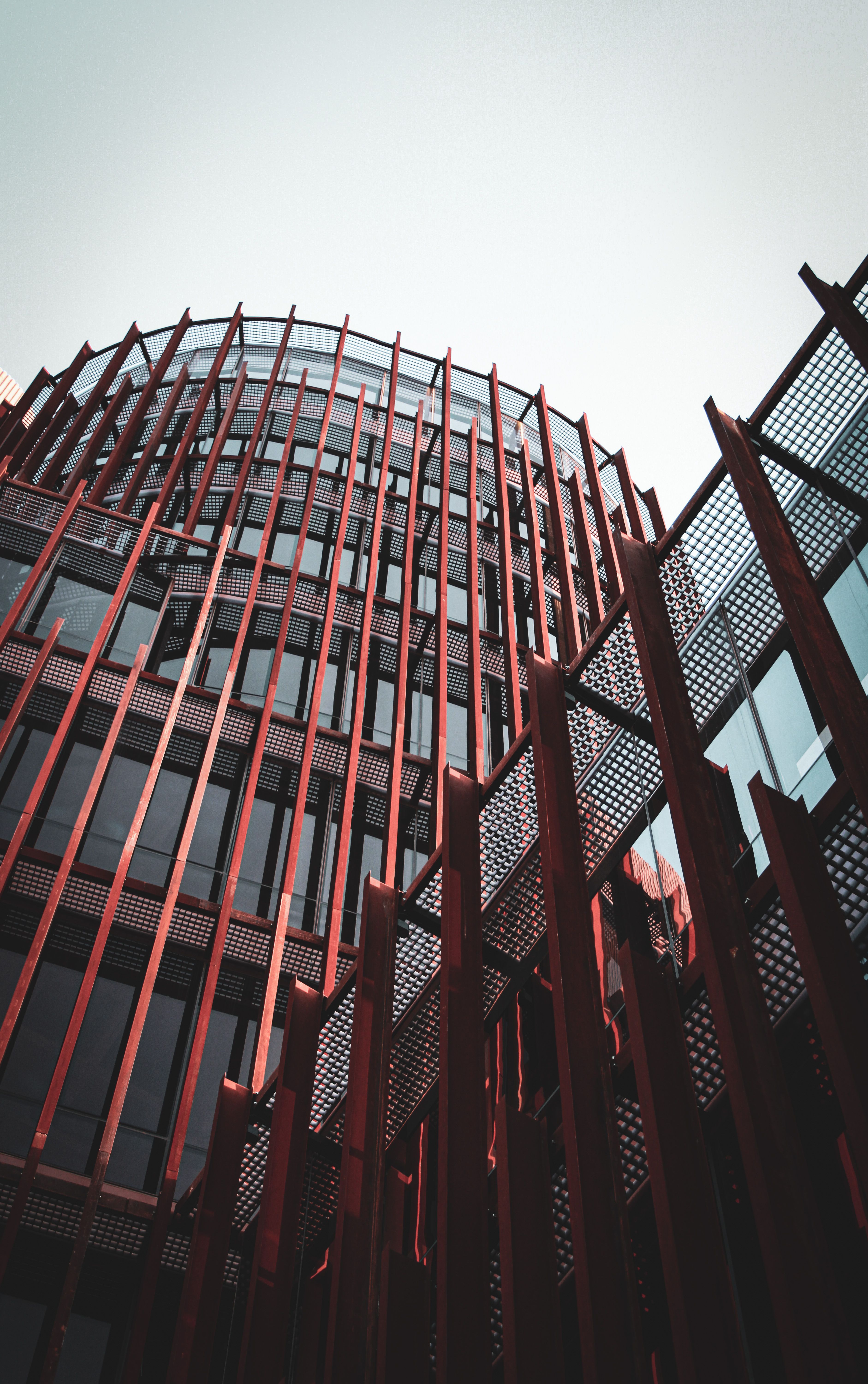 Striking view of a modern glass building with red structural accents in an urban setting.