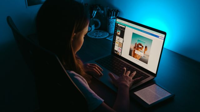 Designer working on a website on a laptop in a dimly lit studio