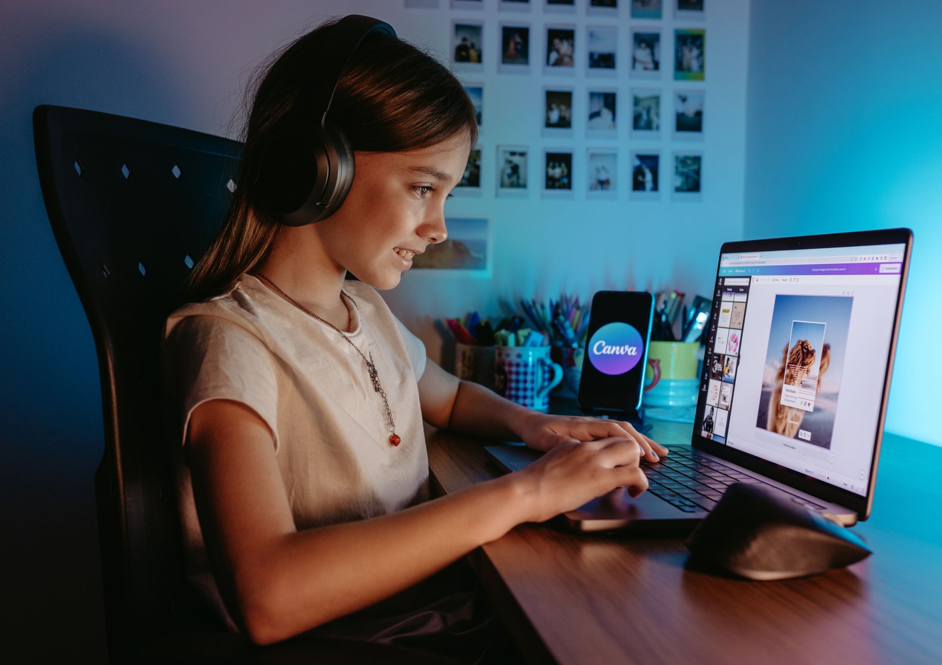 Girl using a laptop with headphones in a cozy indoor workspace for graphic design.