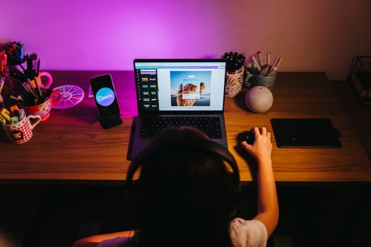 A young girl using a laptop for design work at a colorful home desk setup.