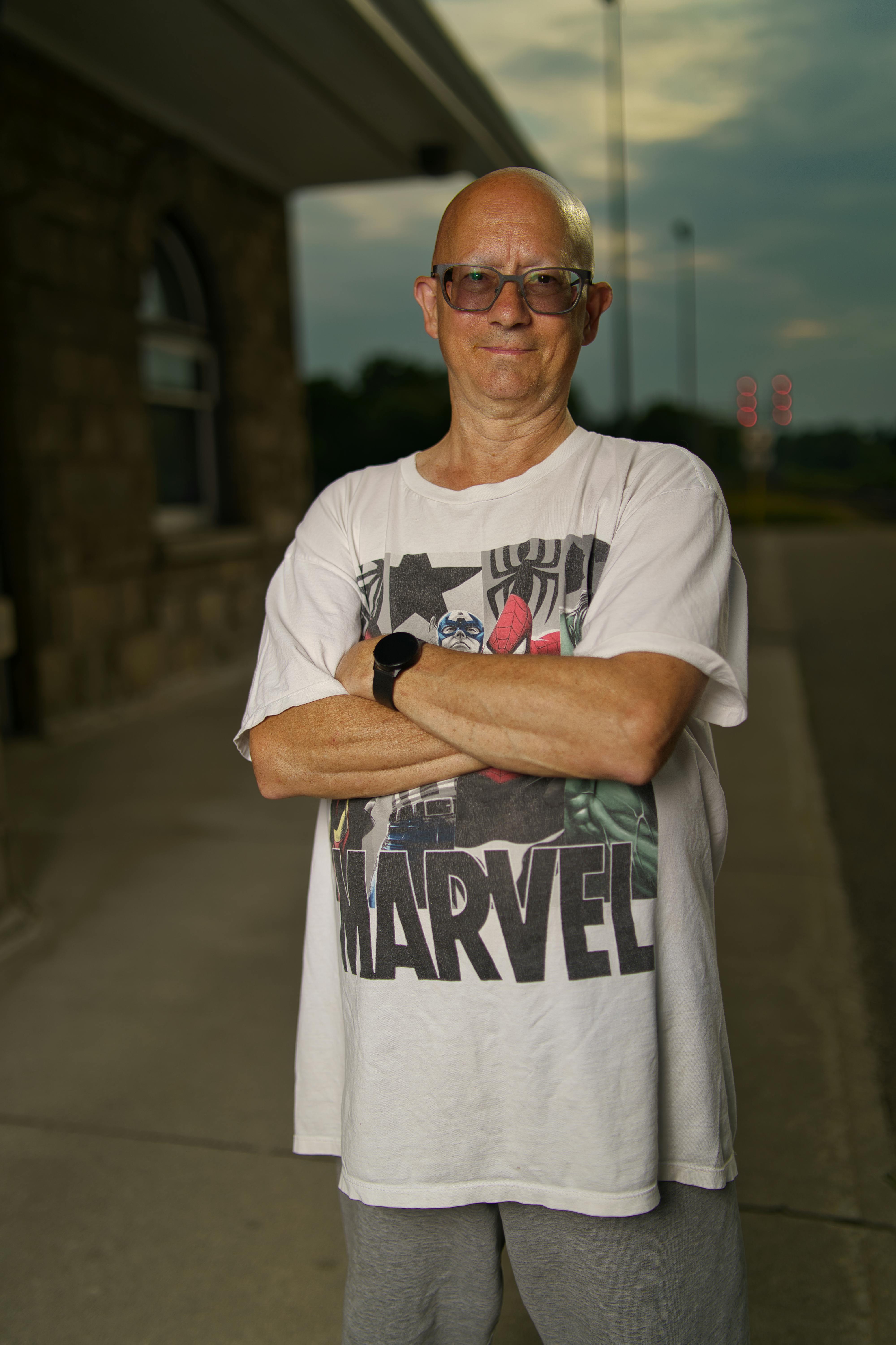 a man in a t shirt standing in front of a building