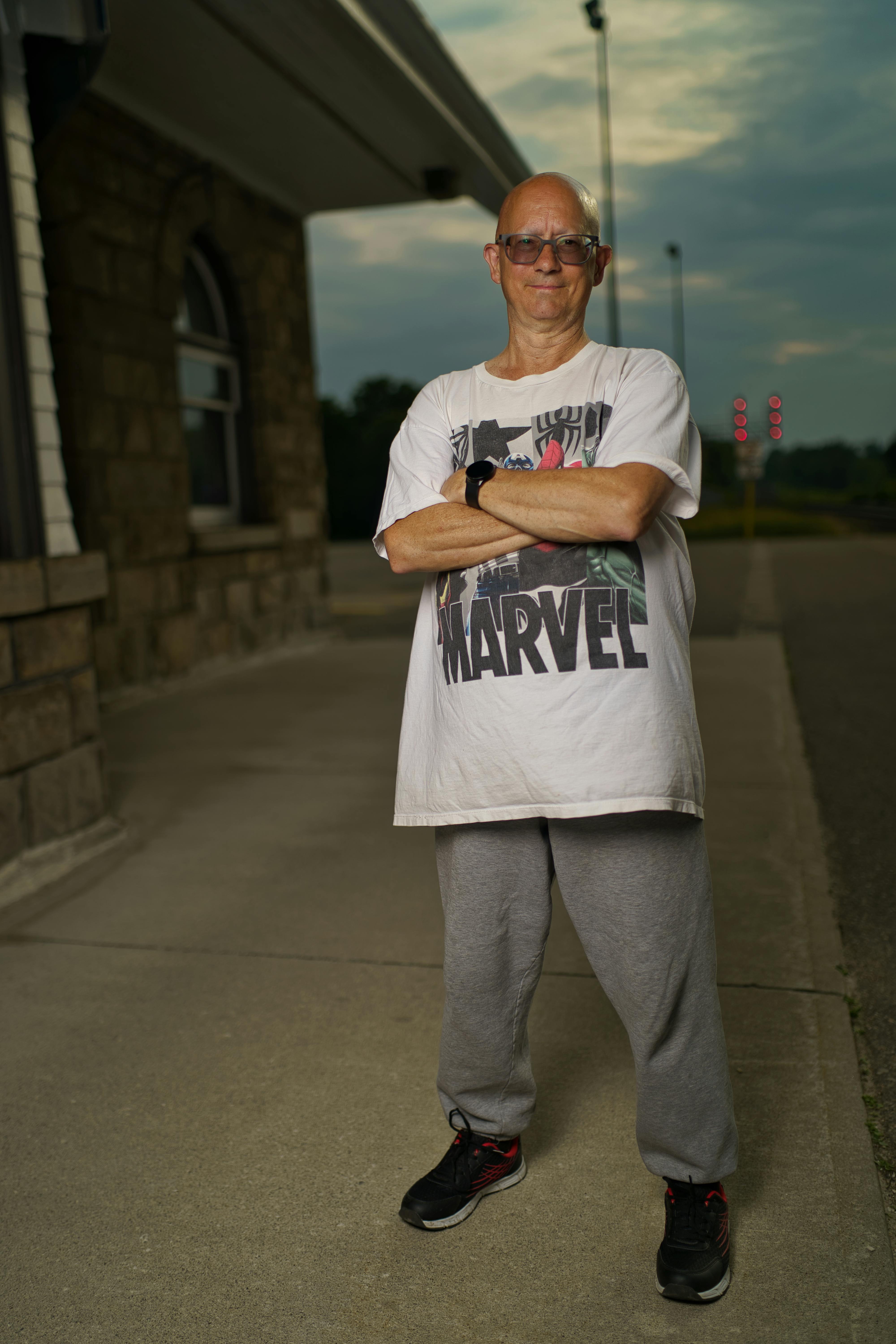 a man standing in front of a building with his arms crossed