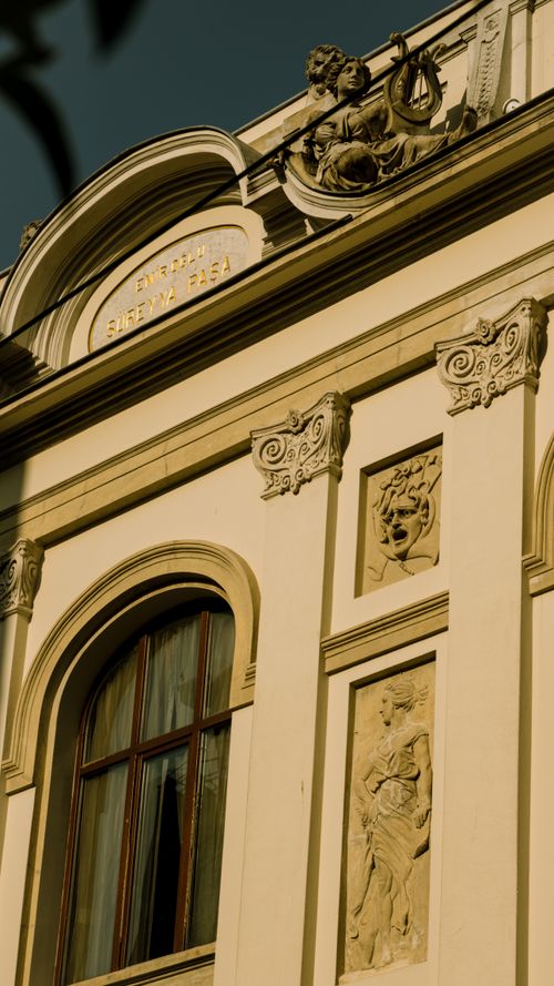 Free Classical building facade with detailed sculptures and arched window. Stock Photo