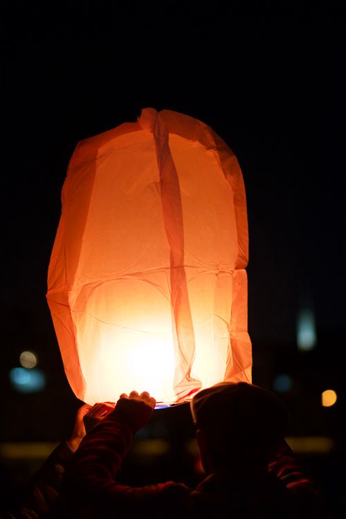 Free A glowing paper lantern being released into the night sky during a festival celebration. Stock Photo
