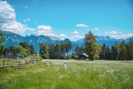 Children play in a picturesque meadow with mountains in Bolzano Vicentino, Italy.