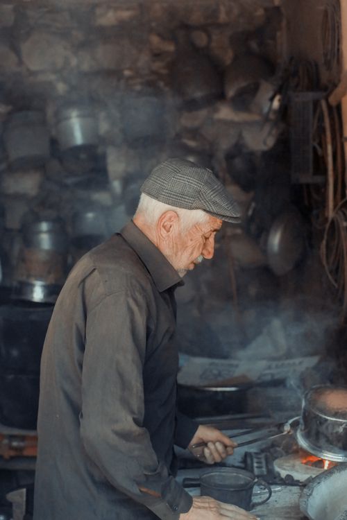 Free A senior man wearing a cap cooking in a rustic kitchen in Arapgir, Malatya, Turkey. Stock Photo