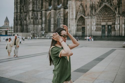Free A woman stands adjusting her hair in front of the iconic Gothic Cologne Cathedral, Germany. Stock Photo