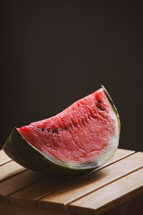 Free Juicy watermelon slice on a wooden table with a dark background, highlighting freshness. Stock Photo
