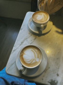Two cups of beautifully crafted coffee on a marble table in a cozy café setting.