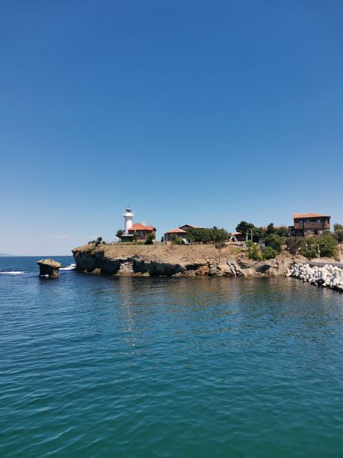 Free Picturesque coastal setting featuring a lighthouse and clear skies over tranquil waters. Stock Photo