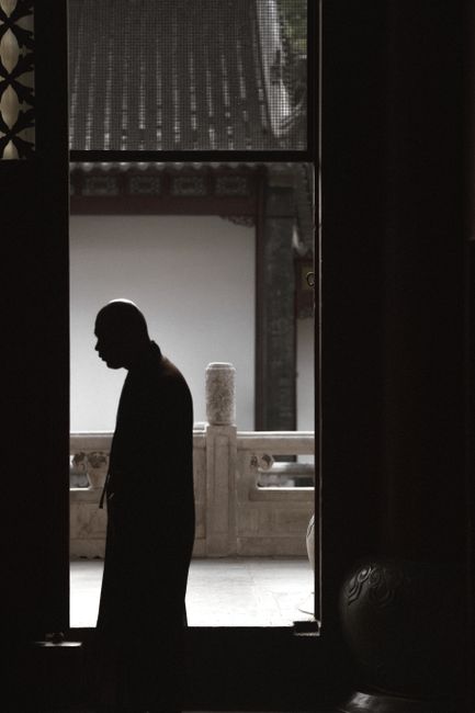 A serene silhouette of a monk stands in a temple's entrance, exuding peace.