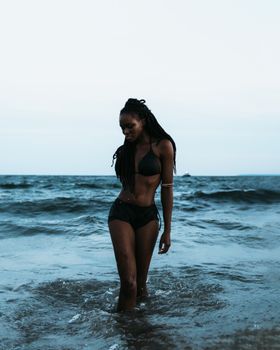 A young woman in a bikini enjoying a refreshing walk along the ocean waves on a sunny day.