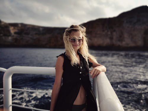 Smiling Woman Standing on Boat Under White Sky