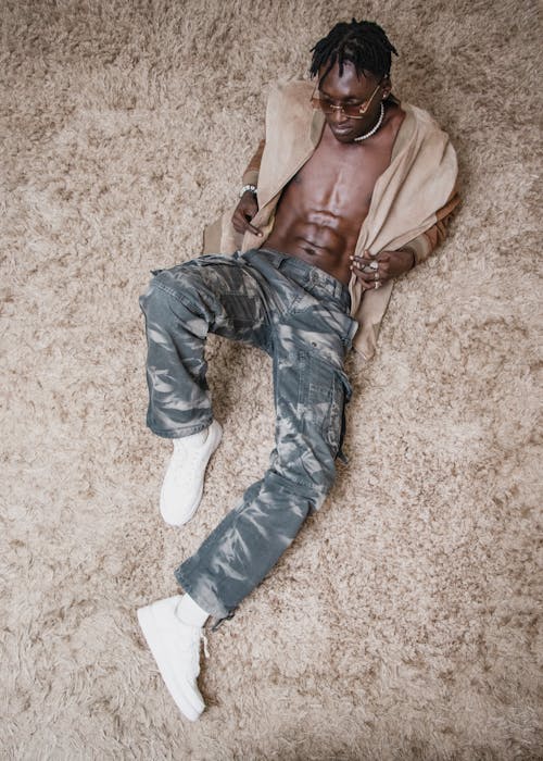 Young Shirtless Man in a Trendy Outfit Lying on the Floor 