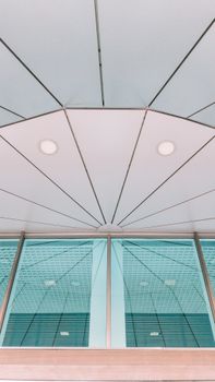 Low angle view of a modern building facade with symmetrical glass panels and geometric lines.