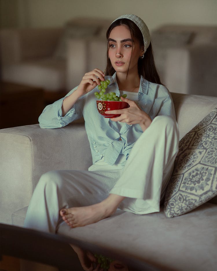 Woman Sitting On Couch And Eating Grapes