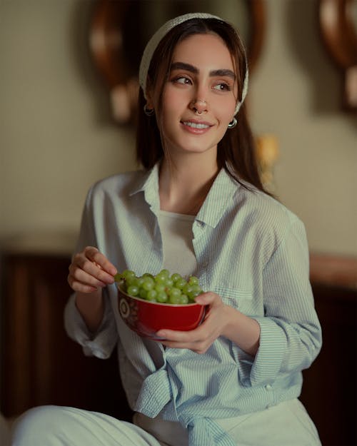 Free Woman in Shirt Sitting with Bowl of Fruit Stock Photo