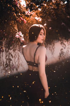 一位年轻女子沐浴在温暖的阳光下，在鲜花盛开的户外摆姿势