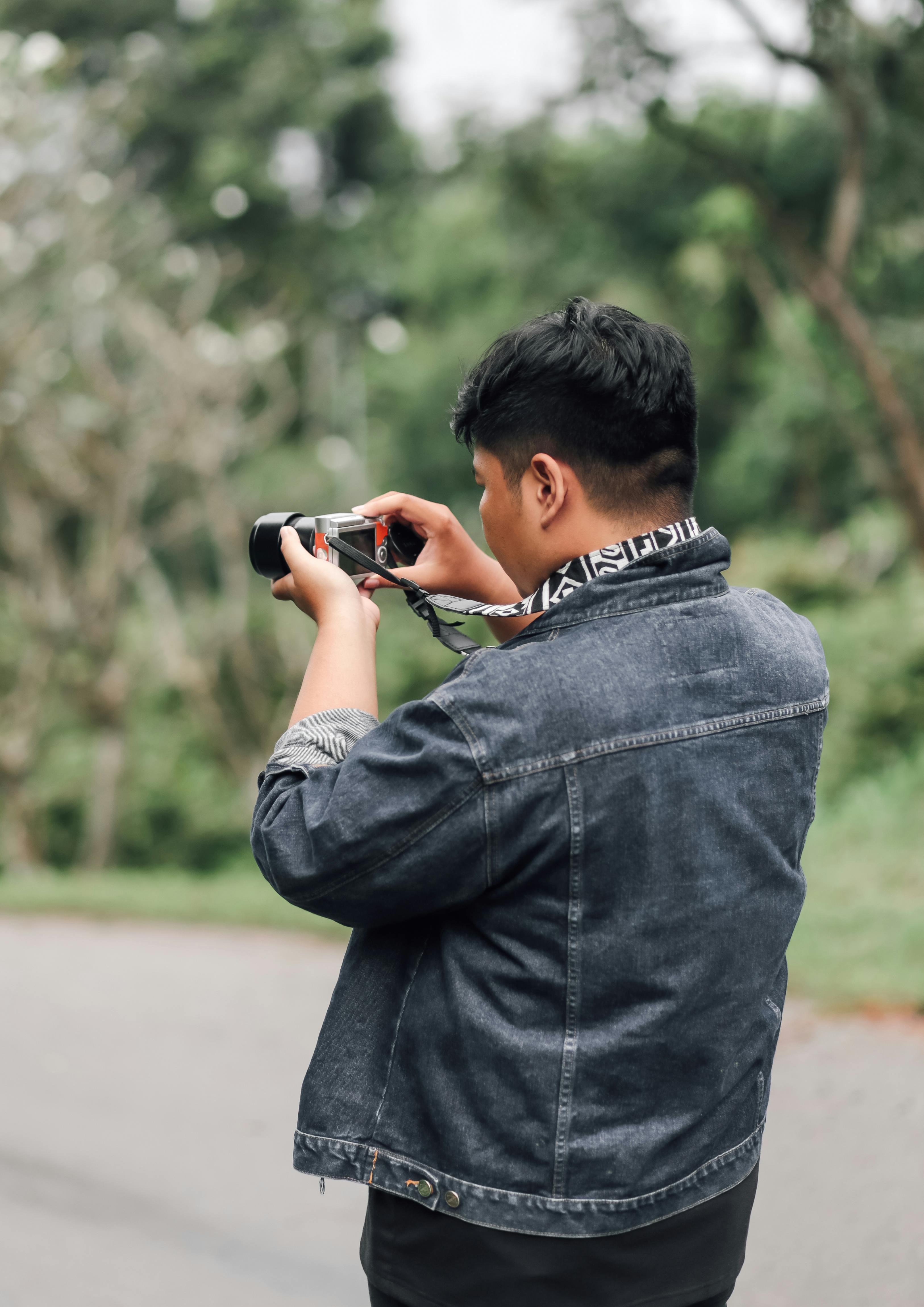 Young Man in Red Jacket Holding Camera · Free Stock Photo
