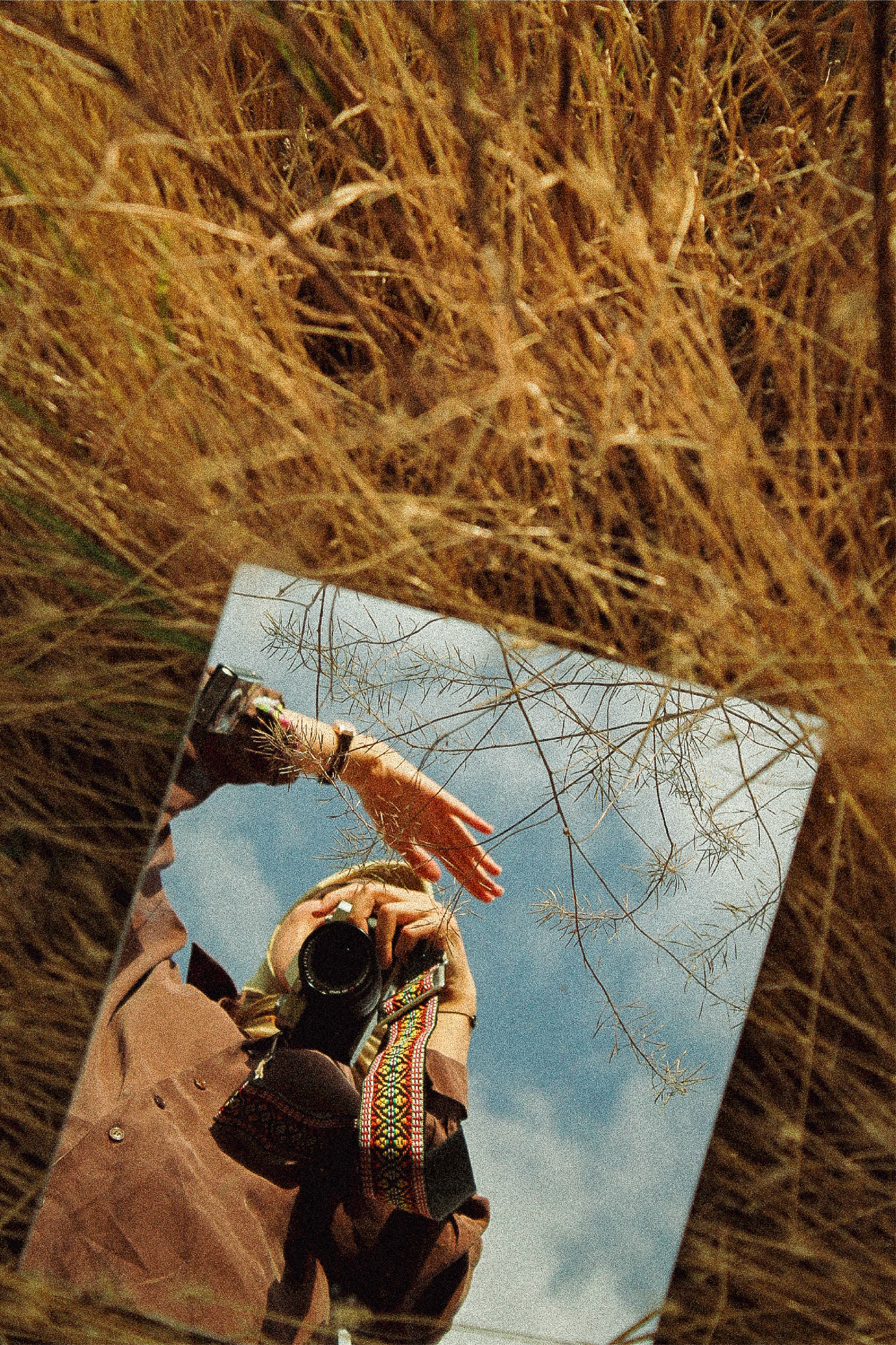 Artistic reflection of a photographer in a field using a mirror.