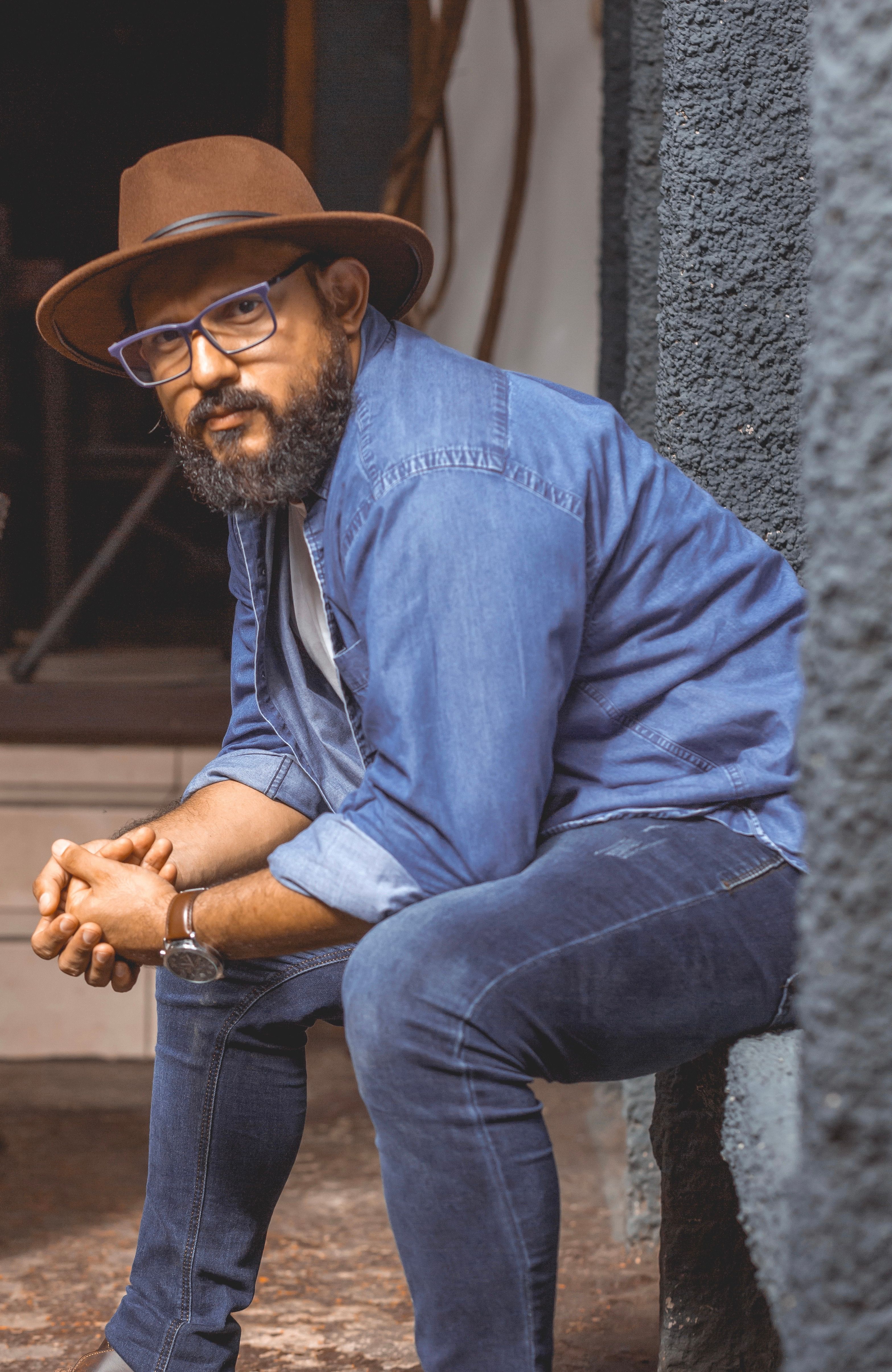 Portrait of a bearded man in denim and hat seated outside in Masaya, Nicaragua.