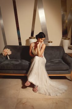 身着白色礼服的新娘令人惊叹地坐在沙发上，室内布置优雅