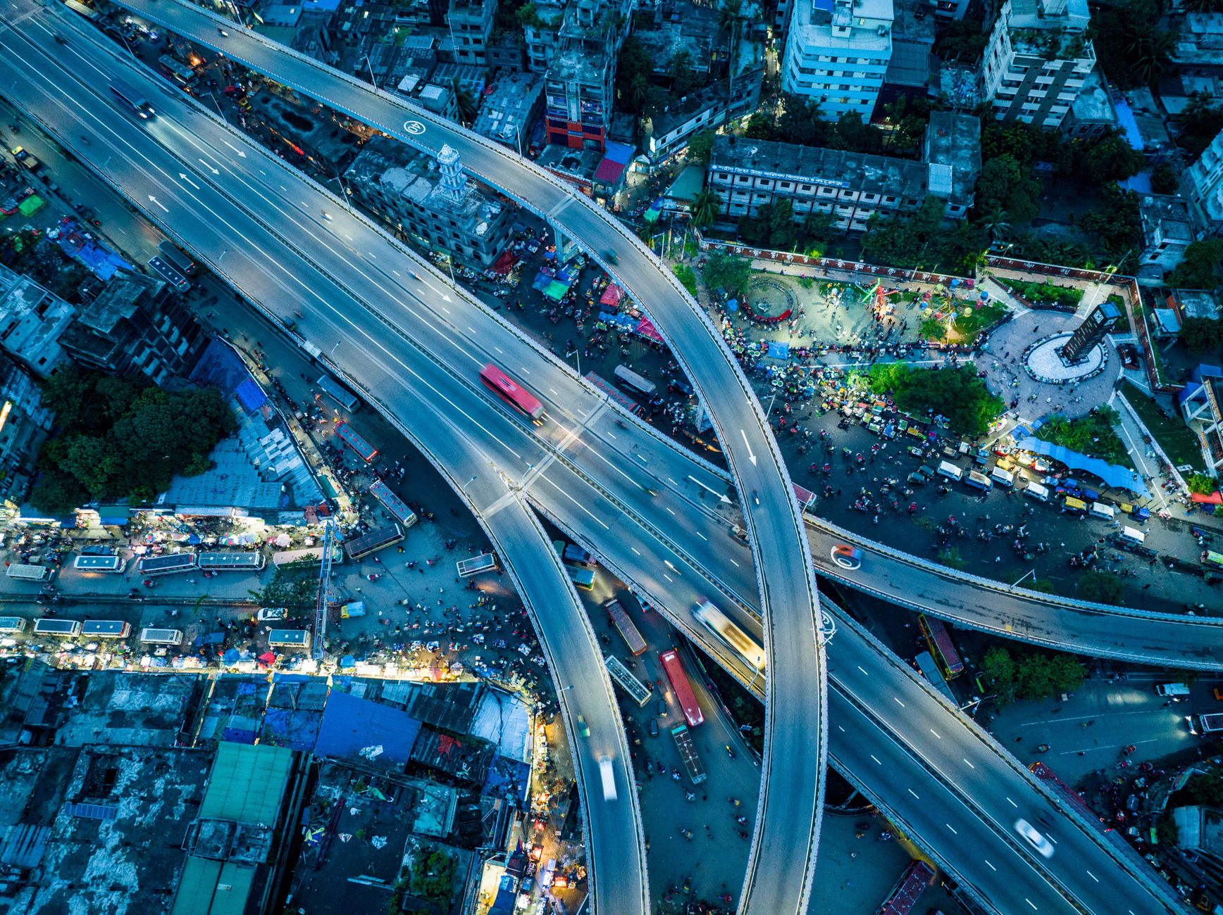 A vibrant aerial view of a busy urban highway interchange illuminated at night.