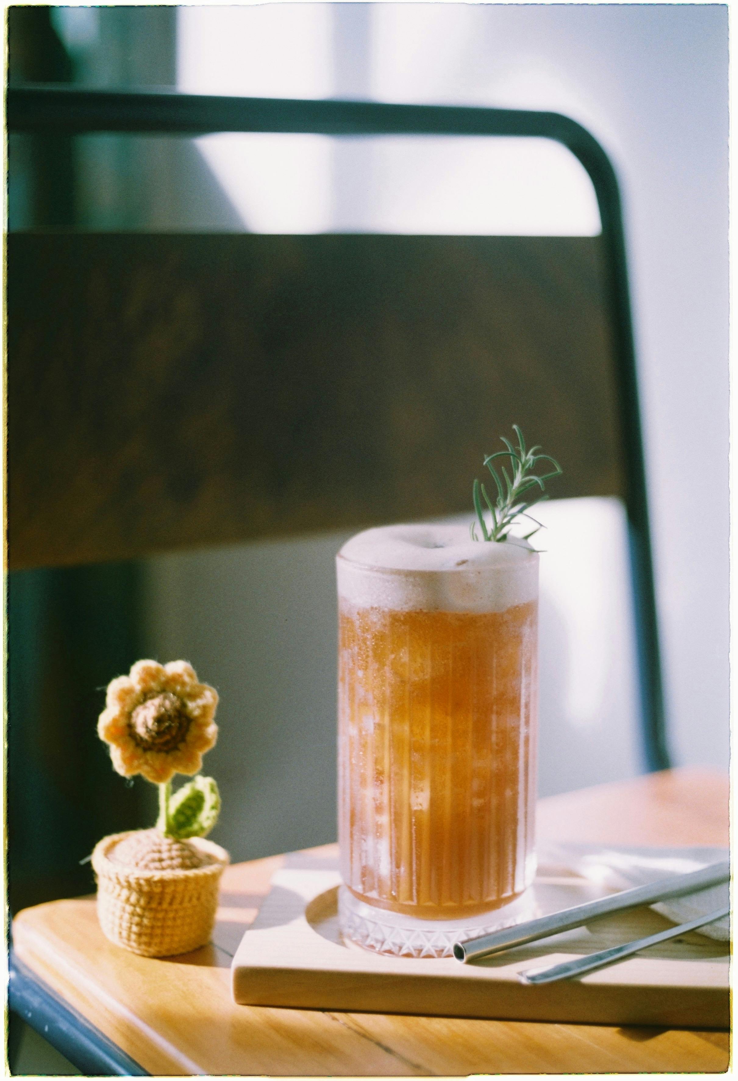 Close-up of a refreshing iced drink garnished with rosemary in a cozy indoor setting.