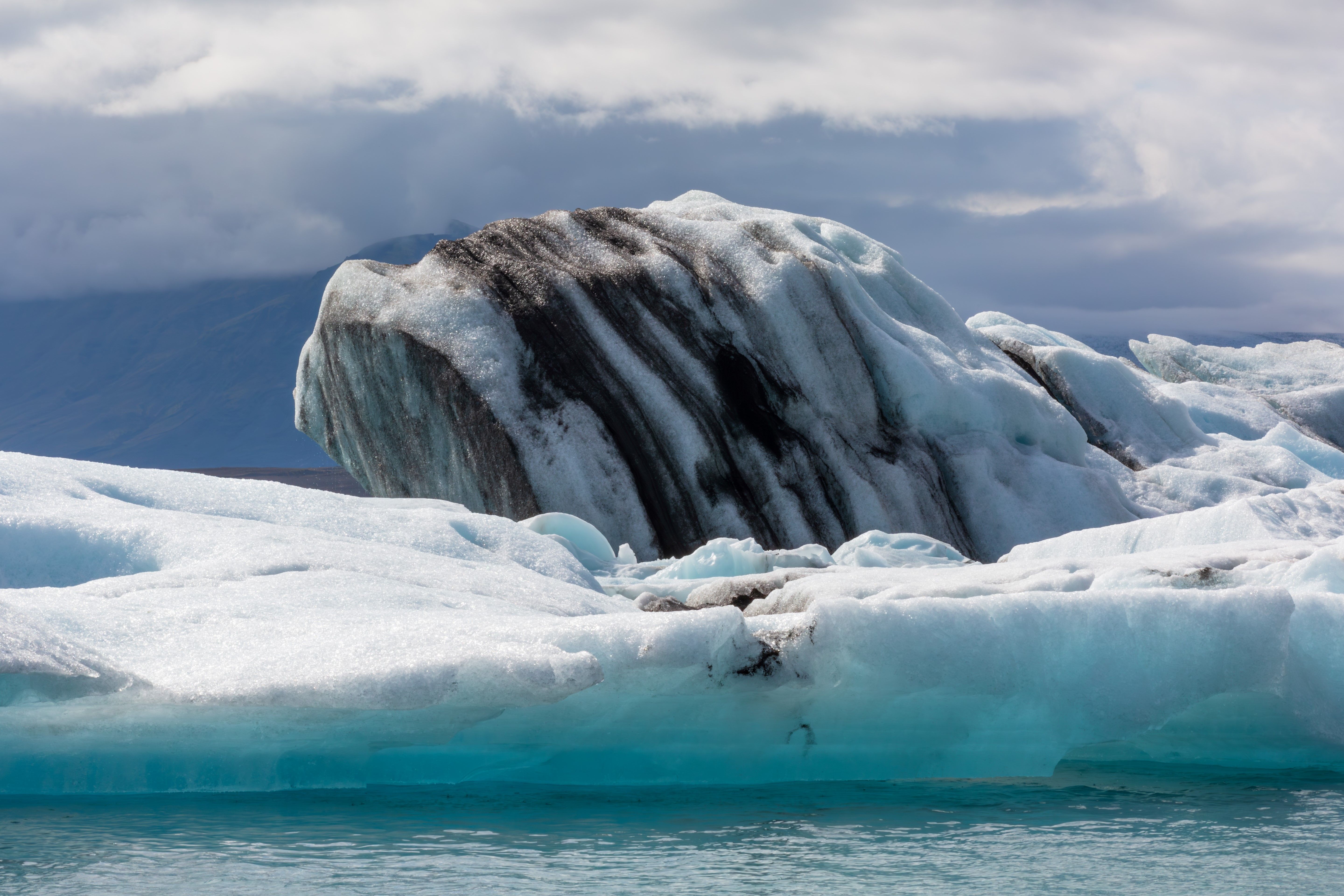A large iceberg floating in the water with a rock in the middle · Free ...