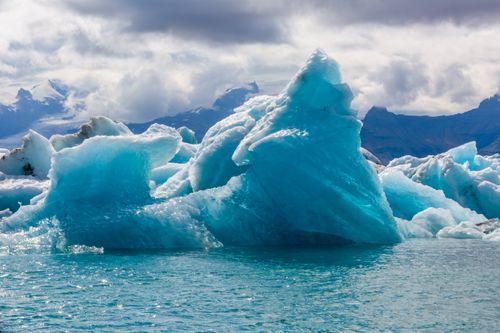 Free A stunning view of a massive blue iceberg floating in clear, cold Arctic waters. Stock Photo