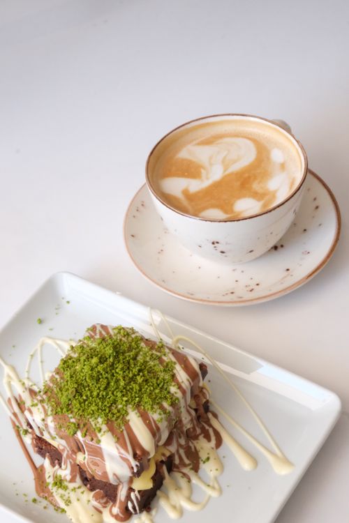 Free A delectable dessert with chocolate and pistachio topping, paired perfectly with a cappuccino. Stock Photo