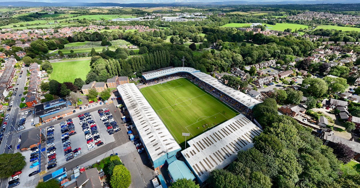 Drone shot capturing Gigg Lane Stadium, surrounded by lush greenery in Bury, England.