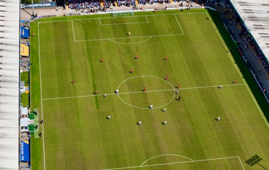 Aerial view of a football match in a sunlit stadium in Manchester.
