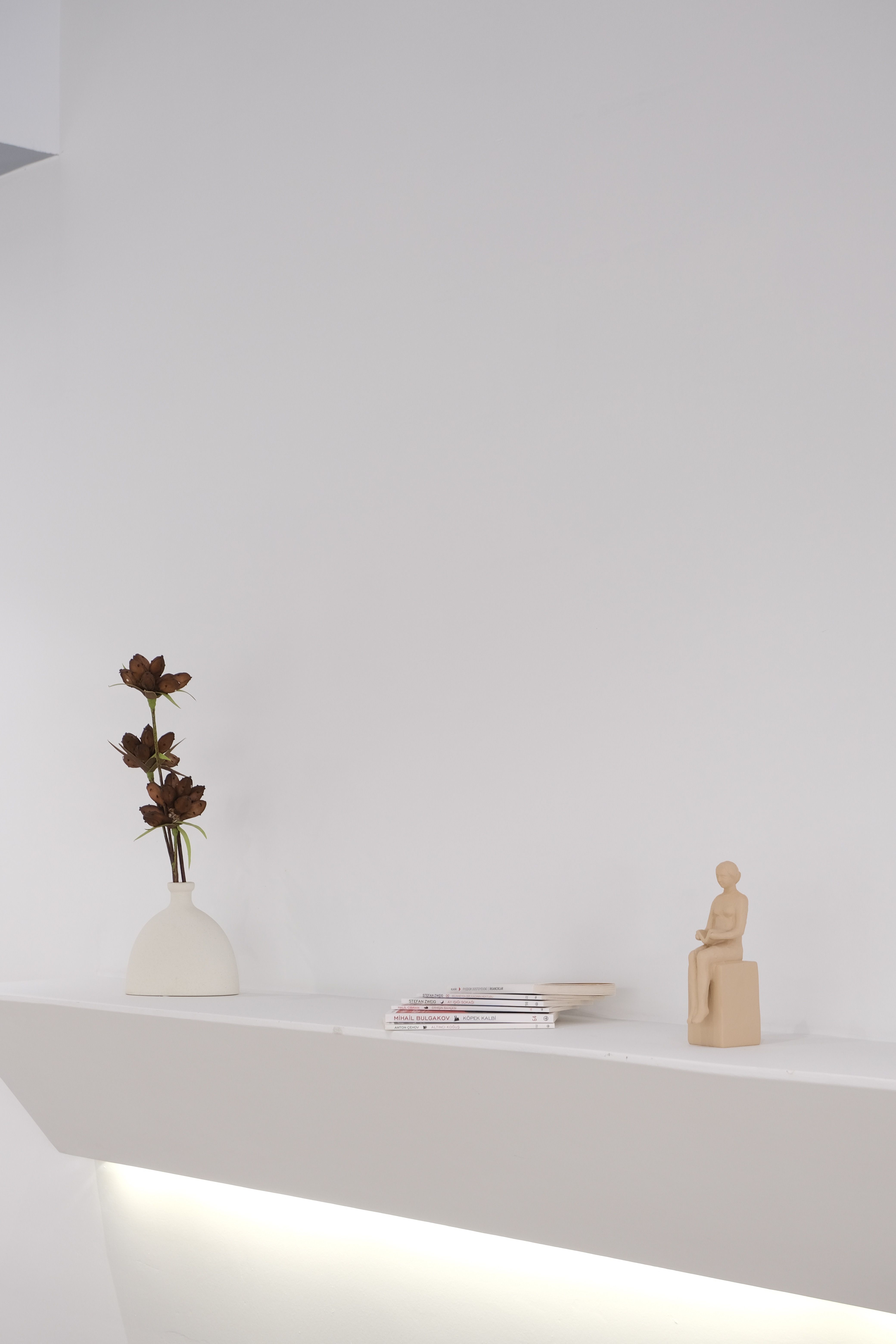 Elegant white shelf decor with figurine and vase for modern interiors.