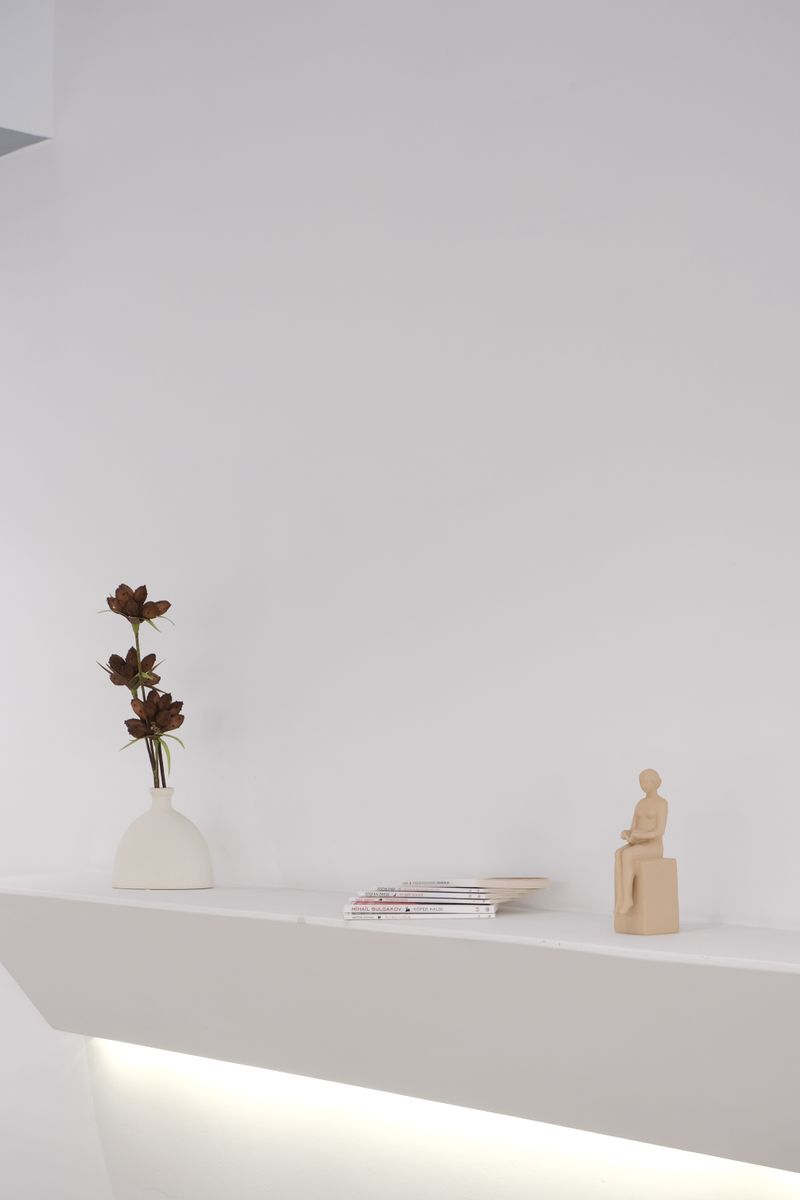 Elegant white shelf decor with figurine and vase for modern interiors.