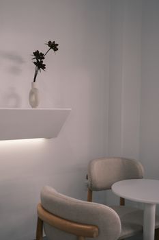 A stylish minimalist interior featuring armchairs, a small table, and decorative flowers.
