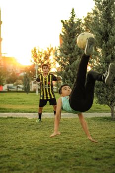 Two boys playing soccer in a park during sunset, showcasing skills and enjoyment.