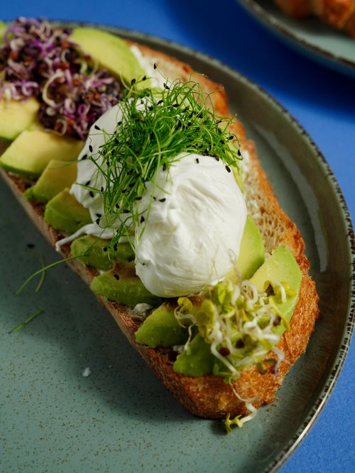 Free Savor a mouthwatering avocado toast topped with poached eggs and sprouts, perfect for brunch. Stock Photo