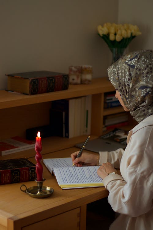 Woman in Hijab Writing on Desk